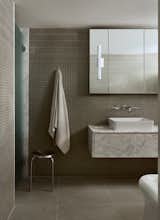 The walls are covered in the same tile as the kitchen, with small square tile topped by vertical pieces closer to the ceiling. The custom floating vanity is white Carrara marble.