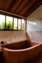 The curving concrete tub has the same color as the floor, to appear as through it's rising out of it.