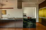 The stainless-steel modules are from Mekal Brasil, and the owners liked the material for its industrial aesthetic and how it nods to professional kitchens. On this end, the green Vitória Régia quartzite is installed to look like a solid cube.
