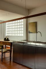 A table that is a family heirloom anchors the end of the run. The linear overhead light can cast illumination up or down, so that prep can be done with precision, when needed, or the owners can create a soft, upward glow when watching TV nearby.