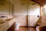 The original ceiling and windows into a garden were kept, while the new vanity is made of orange onyx. Earth-toned ceramic tiles cover the walls.