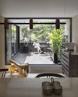 A custom dining table by Studio Urban Form + Objects is surrounded by chairs from Design Bee. An antique trunk has been repurposed into a coffee bar. The caste bronze sculpture seat is by Studio Urban Form + Objects.