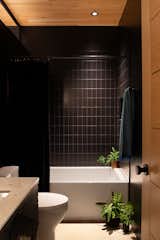 Matte black subway tile from Home Depot surrounds the shower and Kohler tub. The ceiling is natural Douglas fir.