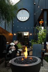 The kitchen opens to the dining area, with a table and benches from Facebook Marketplace. The firepit chairs are from Polywood. The circular window has a custom exterior copper trim by Mission Iron Works.