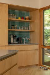 The backsplash tile is from Fireclay in Neptune. When friends come over for parties, they help themselves to a glass from the cupboard. "It feels very organic,
