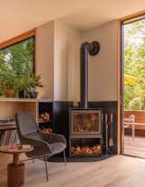 A woodstove by Stuv is anchored by a bookshelf and firewood storage.