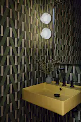 The team at reBuild Workshop relocated the powder room in the plan and covered it in Aviator Olivine cement wall tiles by Zia Tile, with a Pasadena sink in mustard by CONCRETTI and two Dimple® Sconces from RBW. "The yellow sink is really funky, and that's good,