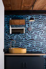 The wallpaper is Pixel by Drop it Modern, paired with the Radar Sconce by Schoolhouse. A Concretti sink sits on a custom plywood and laminate counter, affixed to a Lowdown locker from Mustard Made.