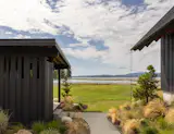 Outdoor, Back Yard, Side Yard, Trees, Shrubs, Gardens, Grass, Hardscapes, and Walkways A path leads from the primary bathroom to the nearby sauna building, which is wrapped in the same cladding as the home.