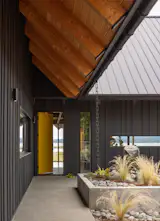 Exterior, House Building Type, Farmhouse Building Type, Metal Roof Material, Wood Siding Material, and Gable RoofLine The front door, painted Benjamin Moore’s Viking Yellow, opens to views of the water.