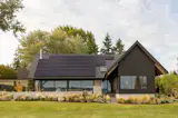 The house was designed with Passive House strategies, including a highly energy-efficient, over-insulated building envelope; a high-efficiency heat pump for heating and cooling paired with an ERV (Energy Recovery Ventilator); and a substantial 17.2kW photovoltaic (PV) array.