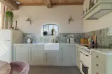 The kitchen cabinets are painted in French Gray by Farrow &amp; Ball, with a composite counter, Equipe tile backsplash, and Enamel wall lamps by Madam Stolz.
