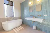 The shower room has a soaking tub, full-sized shower, and tile from Revoir Paris.