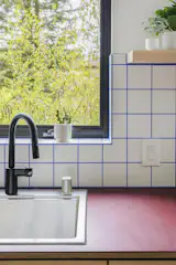 Kitchen, Refrigerator, Cooktops, Dishwasher, Wood Cabinet, Cork Floor, Ceramic Tile Backsplashe, Recessed Lighting, and Drop In Sink The kitchen backsplash is Daltile four-by-four-inch tile in Bright White with custom blue grout, and the countertop is Birch Redstone by Richlite.