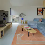 Living Room, Sofa, Coffee Tables, Rug Floor, Storage, Bookcase, Accent Lighting, Lamps, Shelves, Media Cabinet, and Wall Lighting "I’m always a sucker for a dog window," says Butcher of the low-lying pane in the corner of the room, which gives the couple’s canine companion, Zuzz, a view of the driveway and entry.