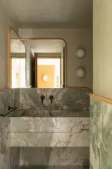 The powder room is encased in mint green marble sourced locally, and used throughout the project.