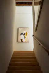 The staircase separates the social level of the main floor from the three upstairs bedrooms. At the top of the stairs is an archival pigment print called Covered in Crowns by Adrian Octavius Walker.