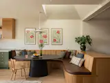The breakfast area has oak millwork by Snake Craft with custom cushions from J&amp;G Upholstery. The PH 5 pendant from Louis Poulsen hangs over the table, and the wall prints are from the Jade Forest Shop. One of the pyramidal frustum roofs with a skylight was placed overhead.
