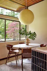 In the breakfast nook, a <a href="https://www.roomandboard.com/">Room &amp; Board</a> table is surrounded by <a href="https://www.bludot.com/">Blu Dot</a> chairs, with a Noguchi pendant overhead.