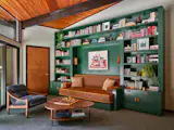 A custom unit now surrounds the couch seating, with wood sconces from <a href="https://cedarandmoss.com/">Cedar &amp; Moss</a>. The accent chair is from <a href="https://www.sohohome.com/us/">Soho Hom</a>e, and the coffee table via <a href="https://www.roomandboard.com/">Room &amp; Board</a>.