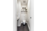 The new powder room includes a wall-hung Toto toilet and wall-hung Duravit sink, white subway wall tiles, and charcoal gray medium hex floor tiles to create a functional space that feels larger than it is. 