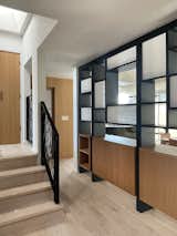 A partition divides the entry area from the dining room, allowing glimpses through it to the view behind, while an organically-designed steel guardrail leads to the main bedroom.