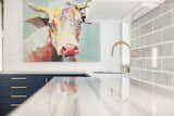 Matte gold hardware and fixtures add a touch of luxury to balance out the colorful farmhouse art, like this oversized cow portrait.