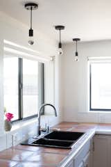 Hangout Lighting pendants; Grohe faucet, Kohler sink, and saltillo tile counters continue the scheme of black, white, and sun-faded earth tones throughout the house