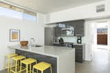 Bright, yellow stools accent a sleek kitchen in the main home.