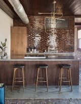 Kitchen, Wood Cabinet, Concrete Floor, Concrete Counter, Rug Floor, Brick Backsplashe, Pendant Lighting, Undermount Sink, and Range In the kitchenette area, seamless walnut cabinets, poured concrete countertops, and glazed brick tiles introduce minimalistic, modern elements.