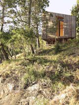 Exterior, House Building Type, and Wood Siding Material Supported on steel supports, the volumes appear to float above the rocks, allowing the natural systems to remain, while blending in between the sky and the ground.  Photo 3 of 9 in A Timber-Clad Sauna in Chile Angles For Lakeside Views
