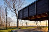 Outdoor, Hardscapes, Grass, Trees, Stone Patio, Porch, Deck, and Woodland The dramatic cantilever provides shade and protection, while leaving views to the lake plentiful.  Photos from A Dramatic Cantilevered Roof Creates a Spacious Terrace Overlooking Lake Michigan