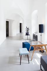 Mid-century modern furniture pieces with blue pastel upholstery and warm wood tones accent the white, bright corridors.