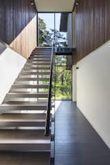 Staircase, Metal Railing, and Wood Tread Open stair treads, composed of rift awn white oak with a custom stain, allow light to pass through.  Photo 6 of 10 in An Incredible Forest Home Leaps Over a Ravine
