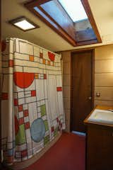 A large, wood framed skylight fills the master bath with daylight.  A Frank Lloyd Wright inspired shower curtain accents the remodeled bath.