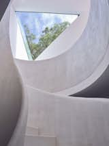 The curvilinear staircase—painted all white—contrasts with the angular forms evident throughout the residence.  