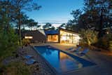 Outdoor, Back Yard, Wood Patio, Porch, Deck, Trees, Swimming Pools, Tubs, Shower, Hardscapes, and Large Patio, Porch, Deck At sunset, the holiday home glows like a shining lantern set within the forest.   Photos from Multiple Modern Cabins Make Up This French Holiday Home