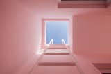 A built-in ladder provides access to the roof deck.  The blue skies contrast with the light pink walls, creating a pastel composition of solids and voids. 