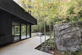 Outdoor, Trees, Decking Patio, Porch, Deck, Boulders, Back Yard, Wood Patio, Porch, Deck, and Hardscapes The exterior deck gracefully meanders its way around the rock formations.   Photo 6 of 17 in This Wood-Clad Home Is Built Into a Serene Mountain Slope