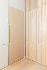 Integrated door pulls omit the need for additional hardware.  The wood pocket door is a geometric pattern of linear wood details. The home's finishes are industrial and minimal, balancing with the exposed wood structure throughout the unit.