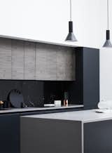 A black marble backsplash contrasts effortlessly with the white walls and light wood panels throughout the home.  Flat panel cabinets add an extra modern flair. 