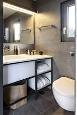 Small but efficient, the bathroom is completed with a vanity, storage, large mirror, and window. 