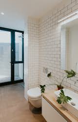 Simple subway tiles decorate the walls of the main floor bath.  A seamless concrete floor leads to directly to the shower with full-height glazing. 