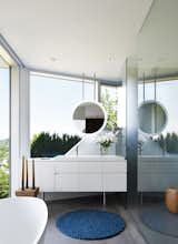 Bath Room, Freestanding Tub, Drop In Sink, Recessed Lighting, Vessel Sink, and Concrete Floor In the master bath, a geometric mirror hangs from the ceiling above, providing continuous views to the hills and sky beyond.

  Photo 7 of 7 in A Contemporary Home Cascades Down the Hillside in Vancouver
