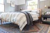 A wool vintage rug from eSaleRugs its below the light oak bed-frame from Article. The sheets are an organic sheet set from Target, adorned by a natural linen duvet cover, and pillow shams and oversized throw from Pom Pom at Home.