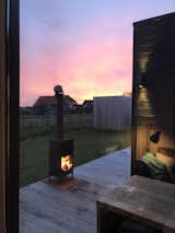 Outdoor, Grass, Back Yard, Wood Fences, Wall, and Wood Patio, Porch, Deck Exterior wood-burning fireplaces draw original camping elements into the luxury of an enclosed, private cabin.

  Photo 3 of 16 in This Chic Cabin Makes Glamping in The Netherlands a Breeze from De Grote Beer