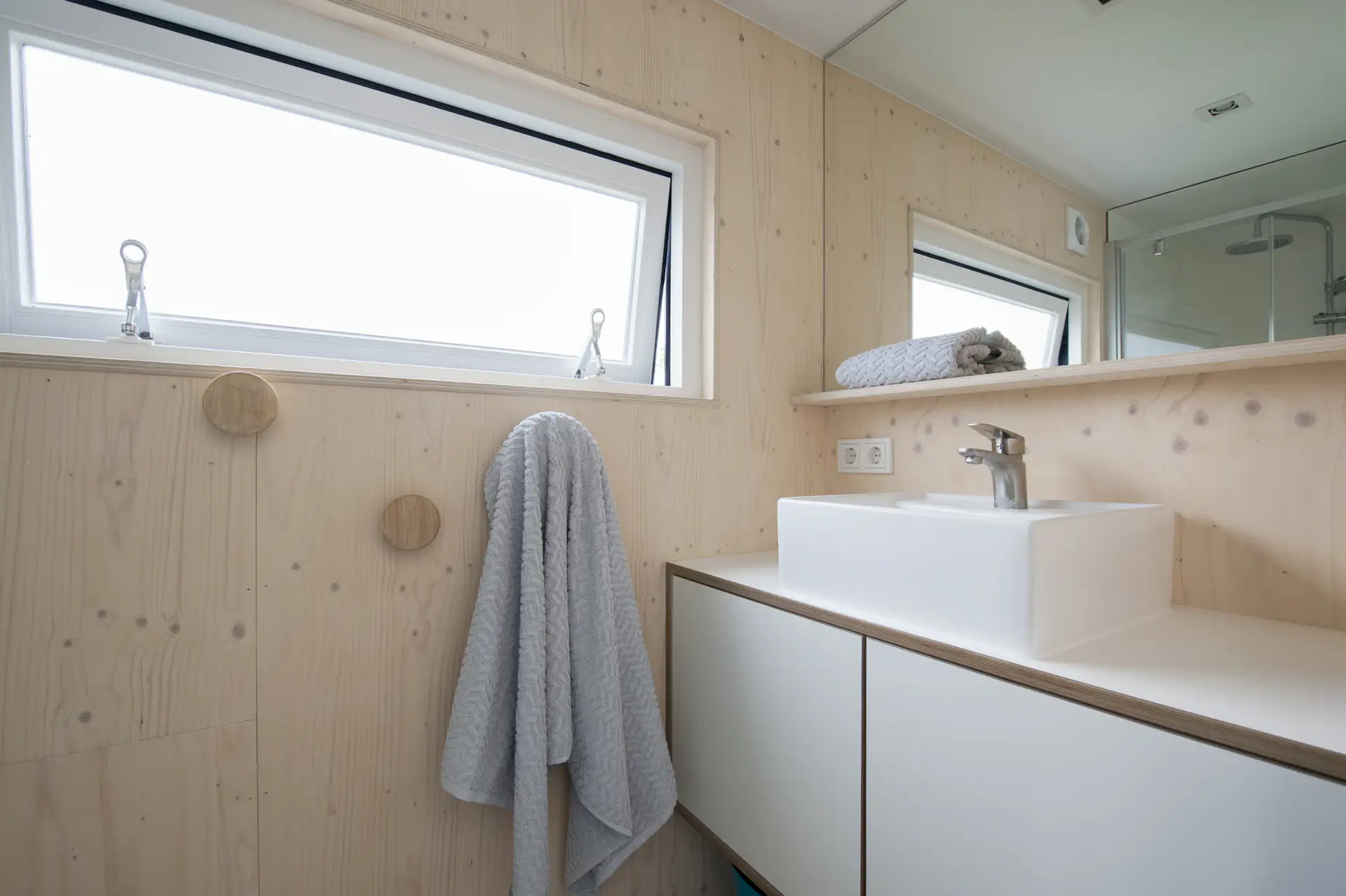 The bath is complete with a floating vanity, vessel sink, walk-in shower, and large mirror.