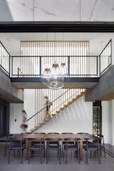 Vertical wood slats continue from the stair treads to the ceiling, emphasizing the openness and grandeur of the open, two-story dining space.

