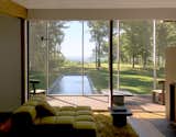 Inside, the focus remains on the landscape and the surroundings. The living space leads to a screened-in porch overlooking a reflecting pool and greenery.
