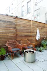 Not only does the backyard have colorful seating and a fire pit, but there is even an outdoor shower hidden by a wood slat fence.